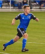 A man wearing a blue soccer uniform running on a field.