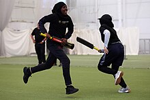 Two girls running between the wickets during a tapeball cricket game