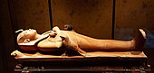 Wooden sculpture depicting Tutankhamun as a mummy lying on a bier with a ba-bird on his left side and a Horus bird on his right