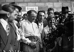 Photo de la remise des prix au vainqueur d'un Grand Prix, ce dernier, tient dans ses mains un trophée.