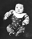 A black-and-white image of an infant in a jumper