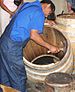 A cooper readies or rounds off the end of a barrel using a cooper's hand adze