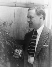 A photograph of Fitzgerald taken by Carl van Vechten three years prior to the author's death. Fitzgerald is facing three quarters to the left next to a small plant and adjacent to a wall. He is wearing a checkered coat and a short square tie with broad horizontal stripes. A burning cigarette is held in his right hand.