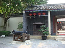 The front entrance of a building labelled "Almshouse" with a cannon in front of it.