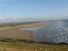 Plage de sable beige vue depuis une colline.