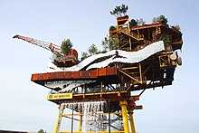 A gas platform repurposed as an art installation with foliage and a waterfall