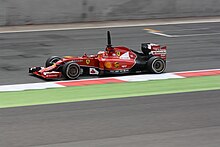 Photographie d'une monoplace de Formule 1 rouge, vue de profil, sur une piste sèche.