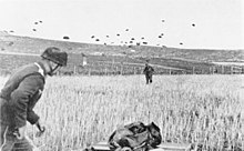 German paratrooper landing with others in the sky behind him
