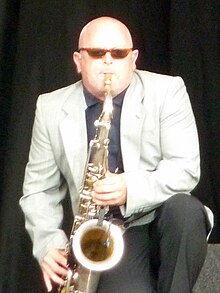 Thompson crouched onstage playing his saxophone