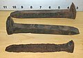 Two unused and one heavily corroded rail spike; the measurement scale shown is inches.