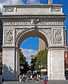 Stone arch with pedestrians walking beneath. The arch is about 10 or 15 times as tall as the people.