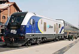 A diesel locomotive with navy blue curved shapes on the front and rear with yellow accents, a black cab area, and Amtrak California logos on the front and sides