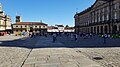 Plaza do Obradoiro as viewed from the Hostal dos Reis Catolicos. The Santiago de Compostela Cathedral is on the left. Large groups of pilgrims clap and celebrate their completion of the Camino de Santigo upon entering the Plaza and congregate in the square, as seen in this image