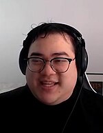 photograph of scarra on stream wearing headphones and glasses