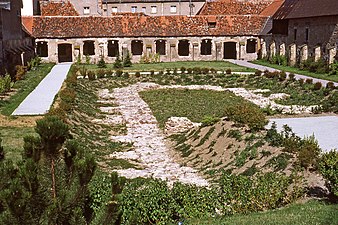 Colour photograph of an excavated courtyard surrounded by a cloister, of which all the bays have disappeared.