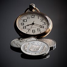 A photograph of a watch and three coins.