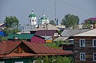 Vue du centre de Ienisseïsk avec des bâtiments en bois et la cathédrale de l'Épiphanie en fond.