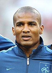 Photo de face de Florent Malouda avec une veste de l'équipe de France de football.