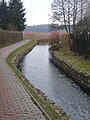 The Niemica River flowing next to a path and under a bridge in Golczewo.