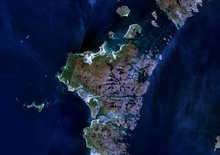 An indistinct image from space of brown and green islands in dark blue water.