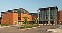 A modern glassy building with a wavy roof