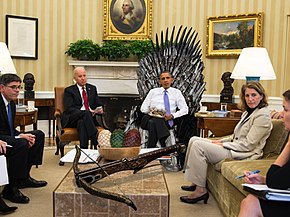 President Obama sits on a digitally-added Iron Throne in the Oval Office of the White House, surrounded by other people