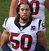 A football player with facial hair and without a helmet