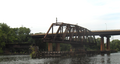 The Philadelphia, Wilmington and Baltimore Railroad Bridge, built 1901-1902 by the American Bridge Company across the Schuylkill River in the Grays Ferry neighborhood in Philadelphia, Pennsylvania, abandoned in open postion ca. 1976. Swing span, 226'-7" long, stone center pier with wood fenders and pilings, and western girder approach. Modern Grays Ferry Avenue bridge in background.