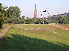 Skulptur Schreiten­der Mensch, hinten die Emmaus-Kirche