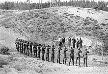 Six men stand in a row, about to be executed by a German firing squad