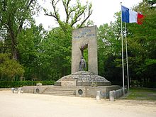 Huge monument to The Blue Devils, with a statue of an Alpine hunter in the center. A large French flag flies to the right of the monument.