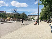 Au lendemain de la réouverture de la place au public, les usagers, observent, reprennent possession de l'espace public. Le cœur centrale de la place ainsi que le parc pour enfants ne sont pas encore rouverts.