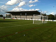 Photographie de la tribune d'un stade de football depuis l'arrière d'un but.