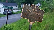 a picture of the marker, a street sign for School Hill road behind it; the marker is in poor shape