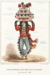 Personnage portant sur sa tête une maison-bateau, un masque et une perruque. Ses vêtements sont très colorés, veste rouge et pantalon rayé, et rappellent de façon caricaturale un uniforme militaire.