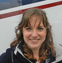 Image of Natasha Baker smiling; she has dark brown, wavy hair and green eyes