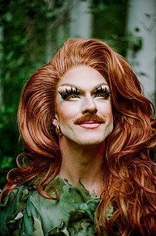 Red-headed drag queen looking up at the sky with a green dress