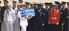 A soldier carries a ceremonial box past other soldiers