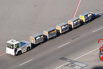 An airport baggage vehicle tows trolleys filled with airmail