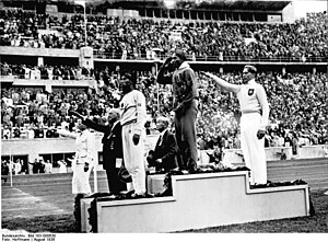 ג'סי אוונס מצדיע לדגל ארצות הברית לאחר שזכה, ב־4 באוגוסט 1936 במדליית הזהב בתחרות הקפיצה לרוחק באולימפיאדת ברלין.
