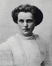 A black and white photo of a young woman posing for a portrait wearing all white with her hair up