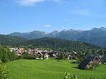 Houses on a mountain plateau, surrounded by a forest and mountains