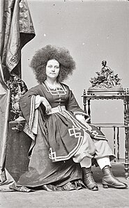 Photographie d'une jeune femme assise aux longs cheveux crépus.