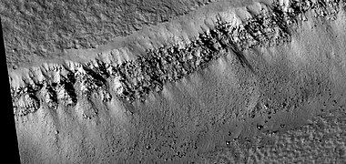 Close view of layers and boulders in the wall of a trough, as seen by HiRISE under HiWish program