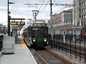 A light rail train at a surface station in the median of an urban street