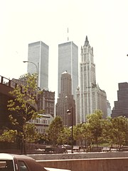 Photograph of the Woolworth Building in 1985 with several sky scrapers, including the towers of the former World Trade Center in the background
