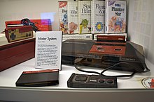 A video game console with numerous video game boxes behind it.