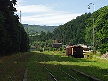 ドブシナー鉄道駅終端から伸びるドブシナー市有林企業の原木積出用専用線。中央奥に東部スロバキア採石砂利国有会社時代のアスベスト積出施設遺構が見える（2015年）