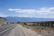 highway descending into a valley with a solitary billboard and building visible in the distance