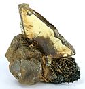 Titanite crystal that is totally gemmy and transparent, with a light olive-green color, perched on matrix of calcite and epidote